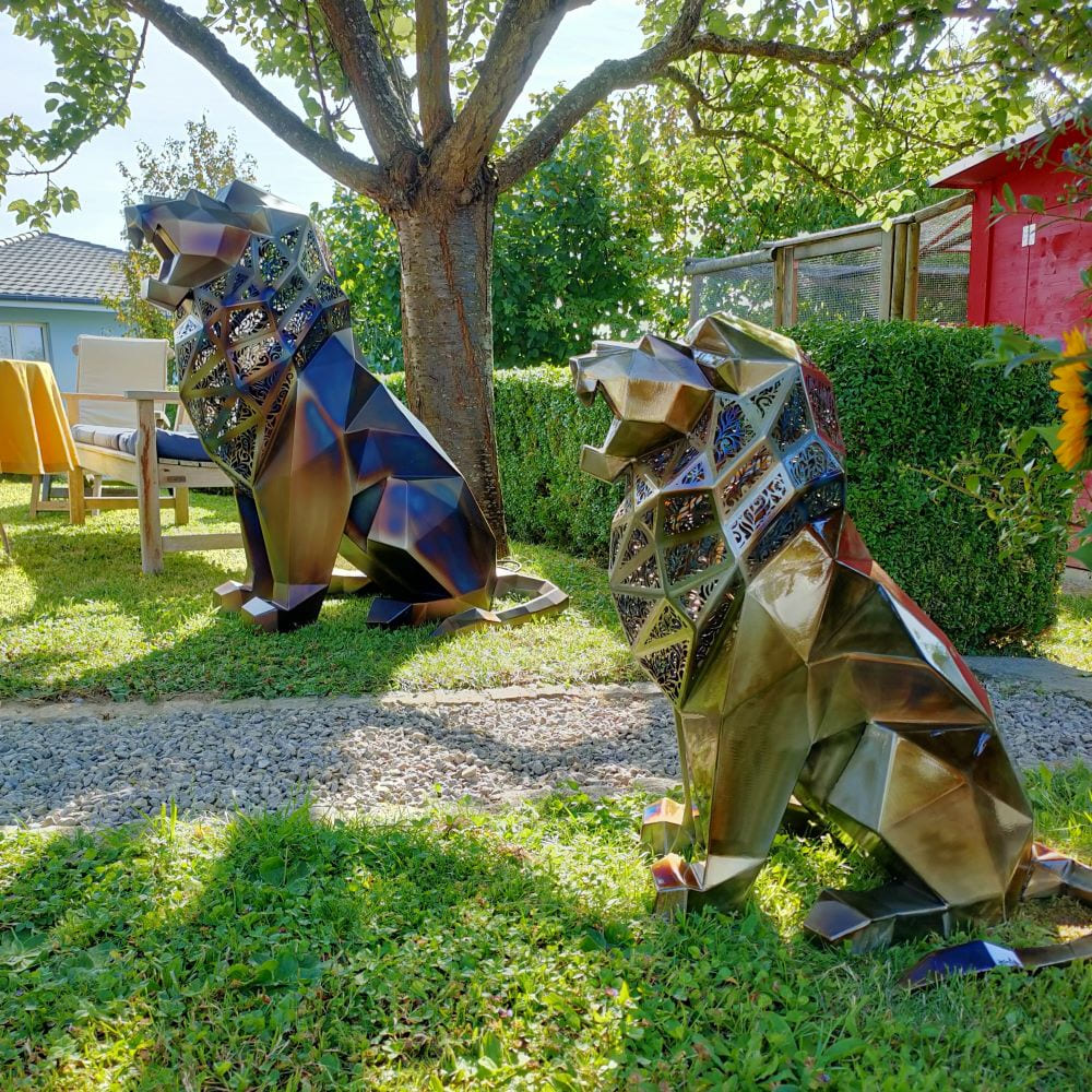 Majestic geometric lion duo sculptures with intricate laser-cut designs, displayed outdoors